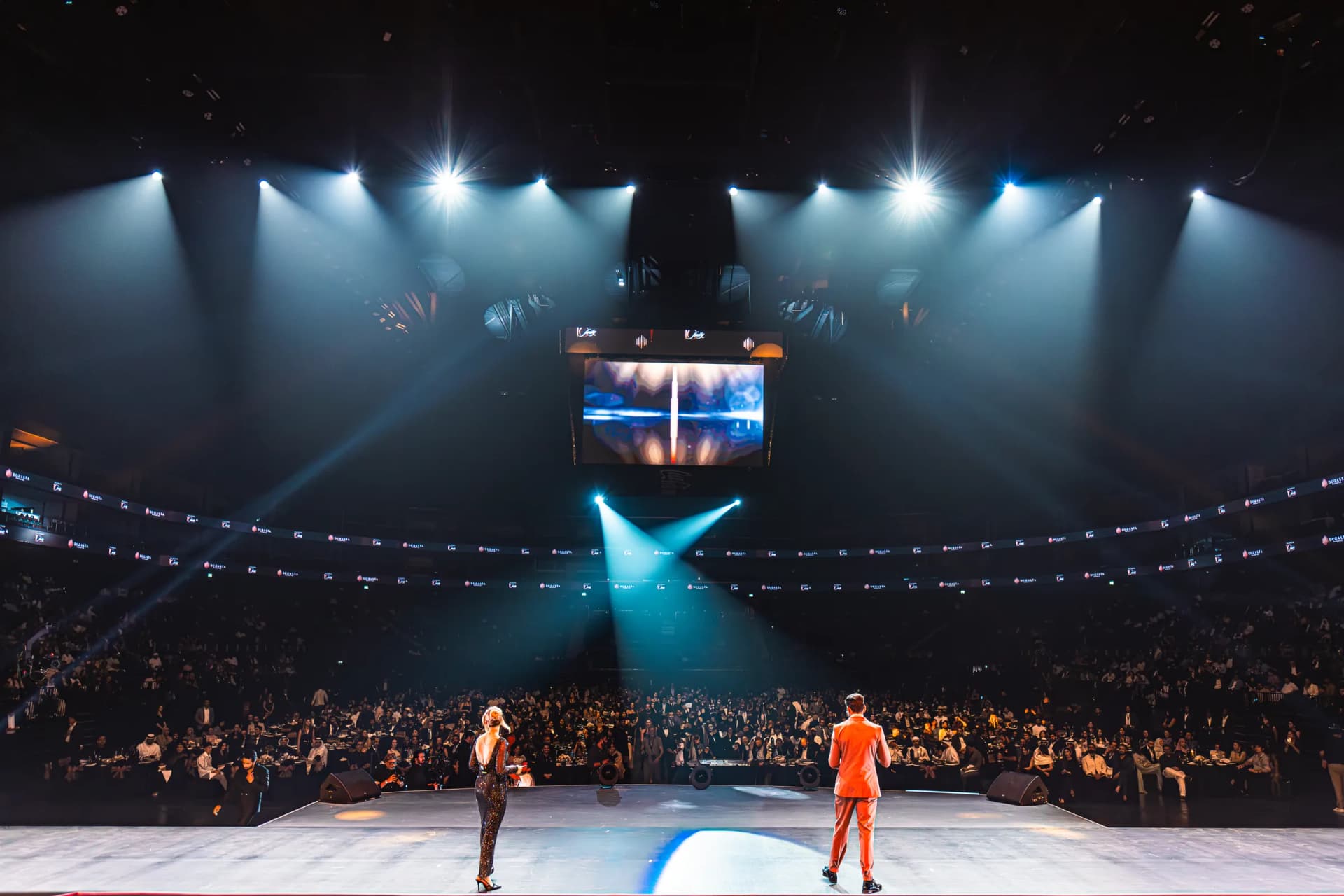 Darryl Rees on stage at a large arena event in Dubai facing a packed audience