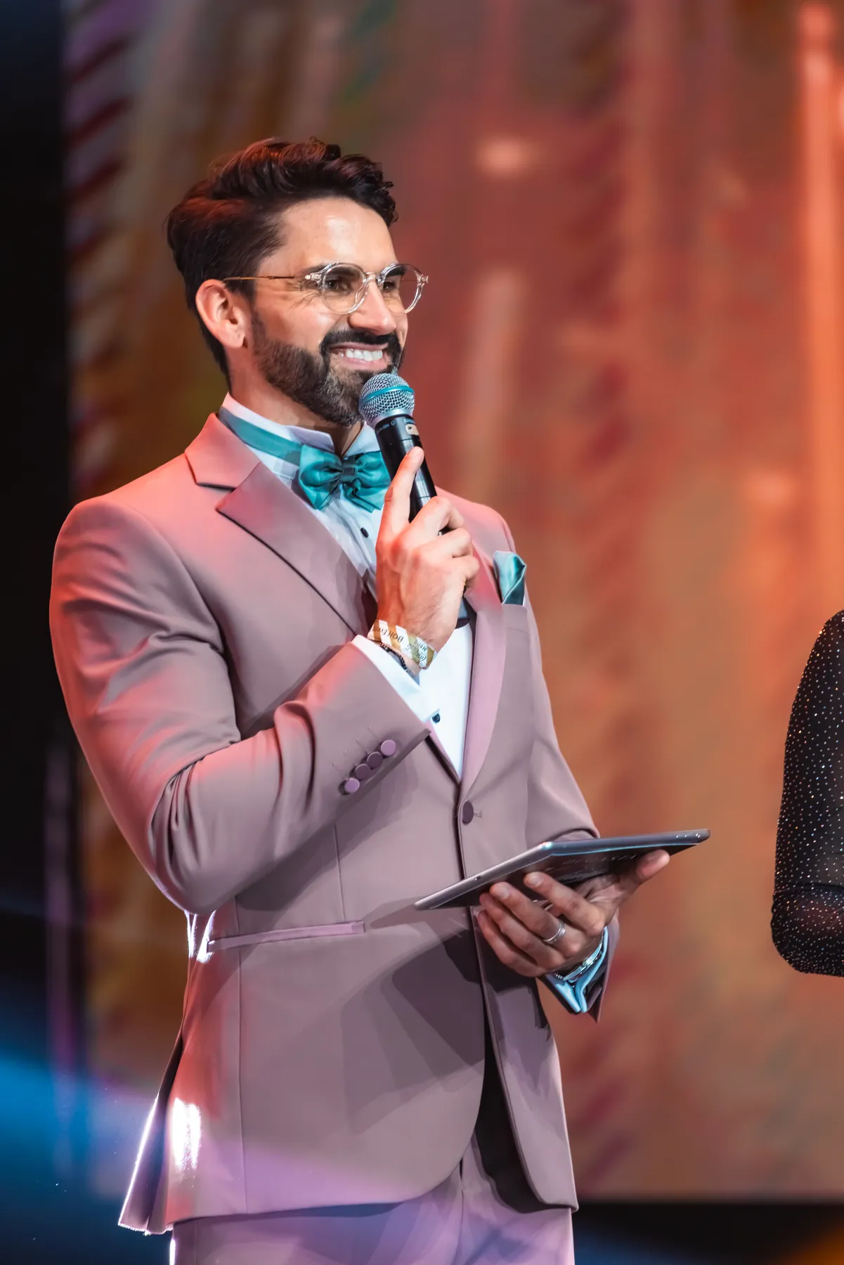 Darryl Rees on stage in a pink suit as wedding MC in Dubai
