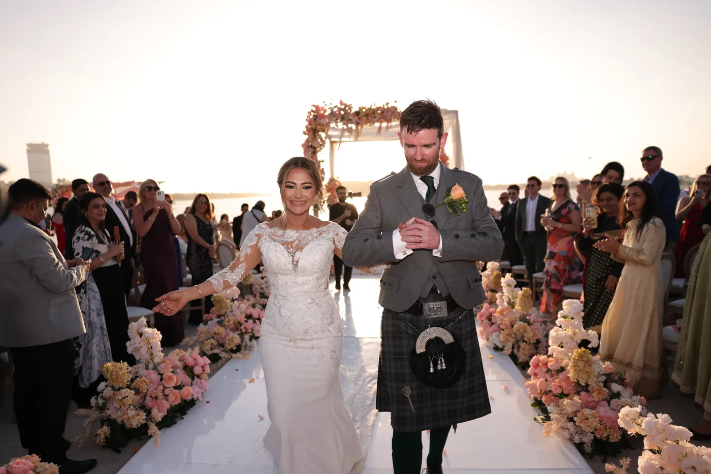 Newlyweds walking back down the aisle after their Dubai beach wedding ceremony