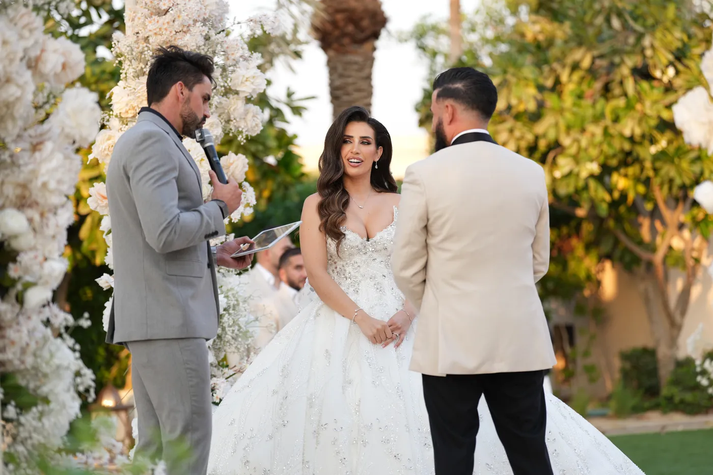 Darryl Rees leading wedding vows for a bride and groom under a floral arch